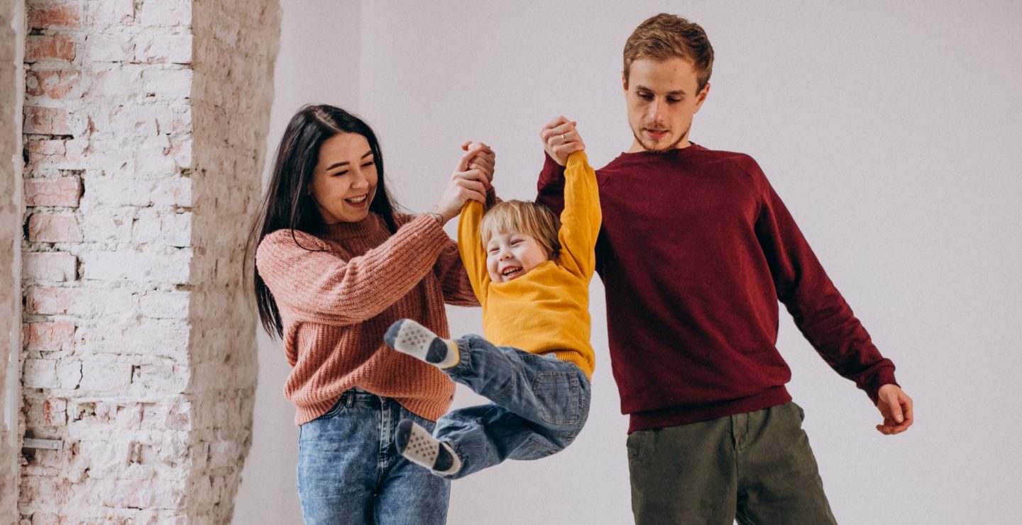 Young family with little son together on grey background
